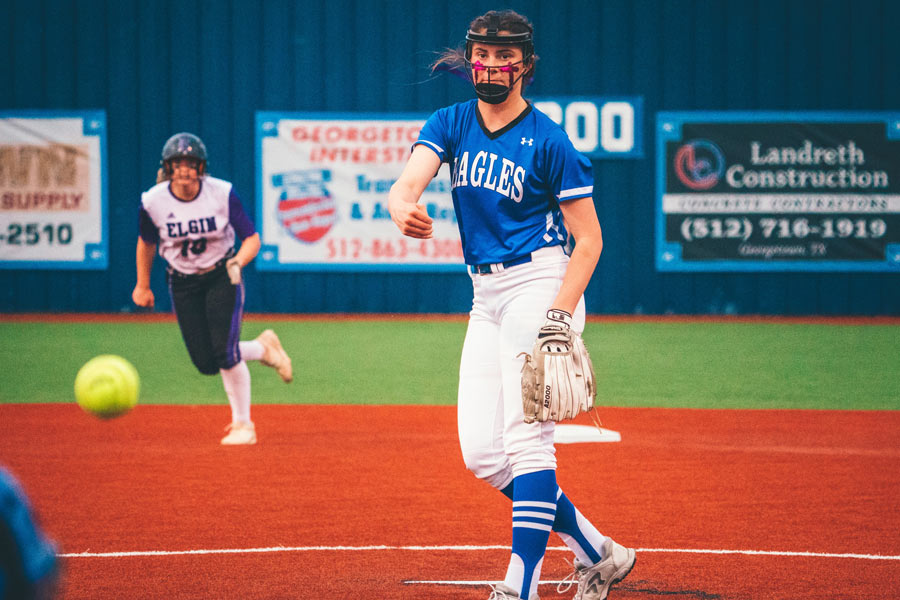 Female softball pitcher releasing the ball to home plate on a beautiful softball field.